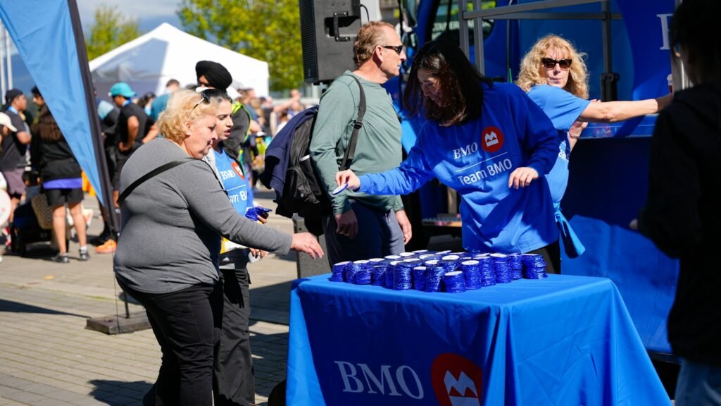 Staff at a branded booth hand out free items to visitors at an outdoor event