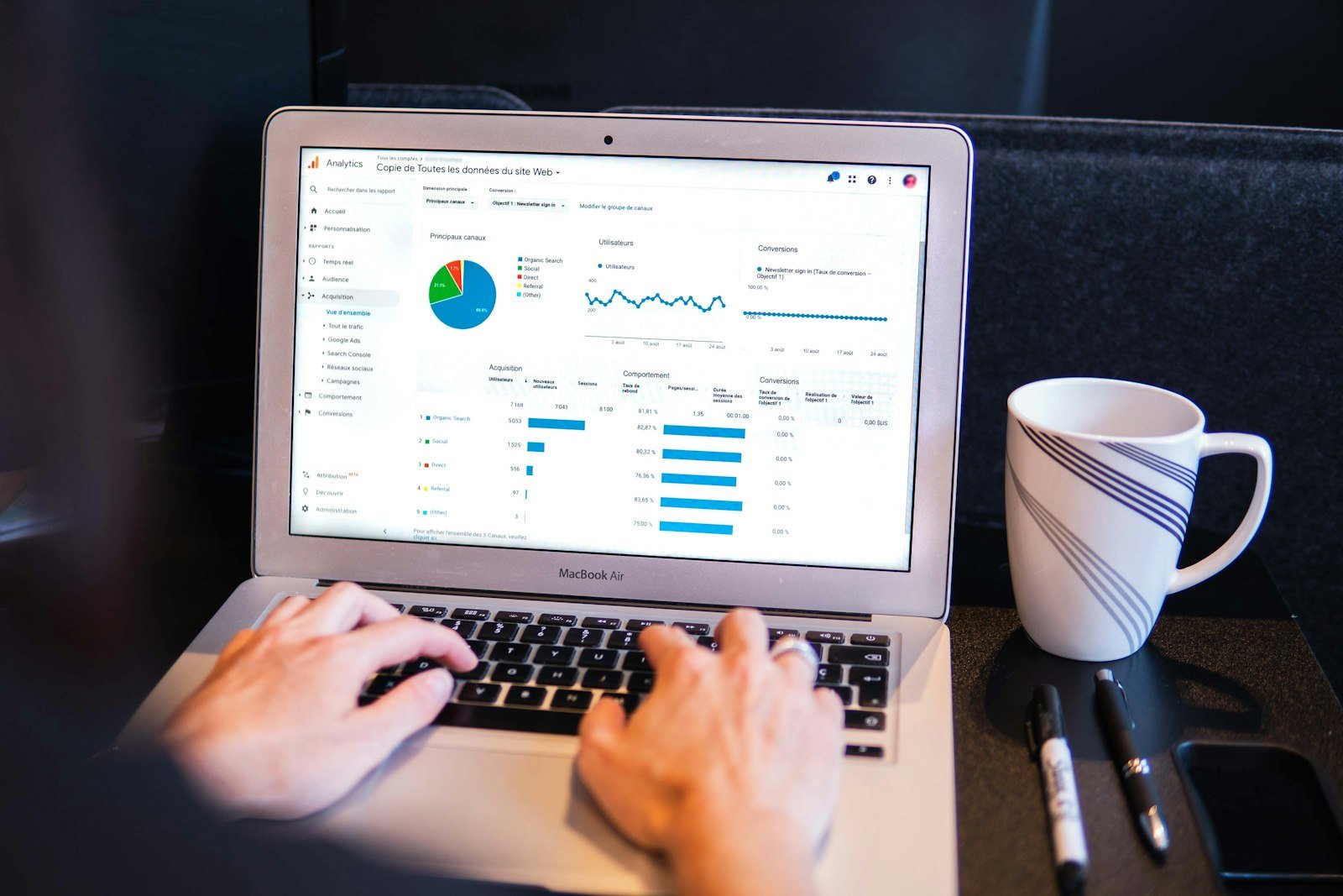 Hands typing on a laptop that shows website analytics charts