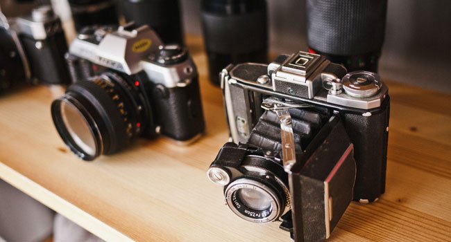 Cameras on a wooden table, ready to shoot simple ad creative