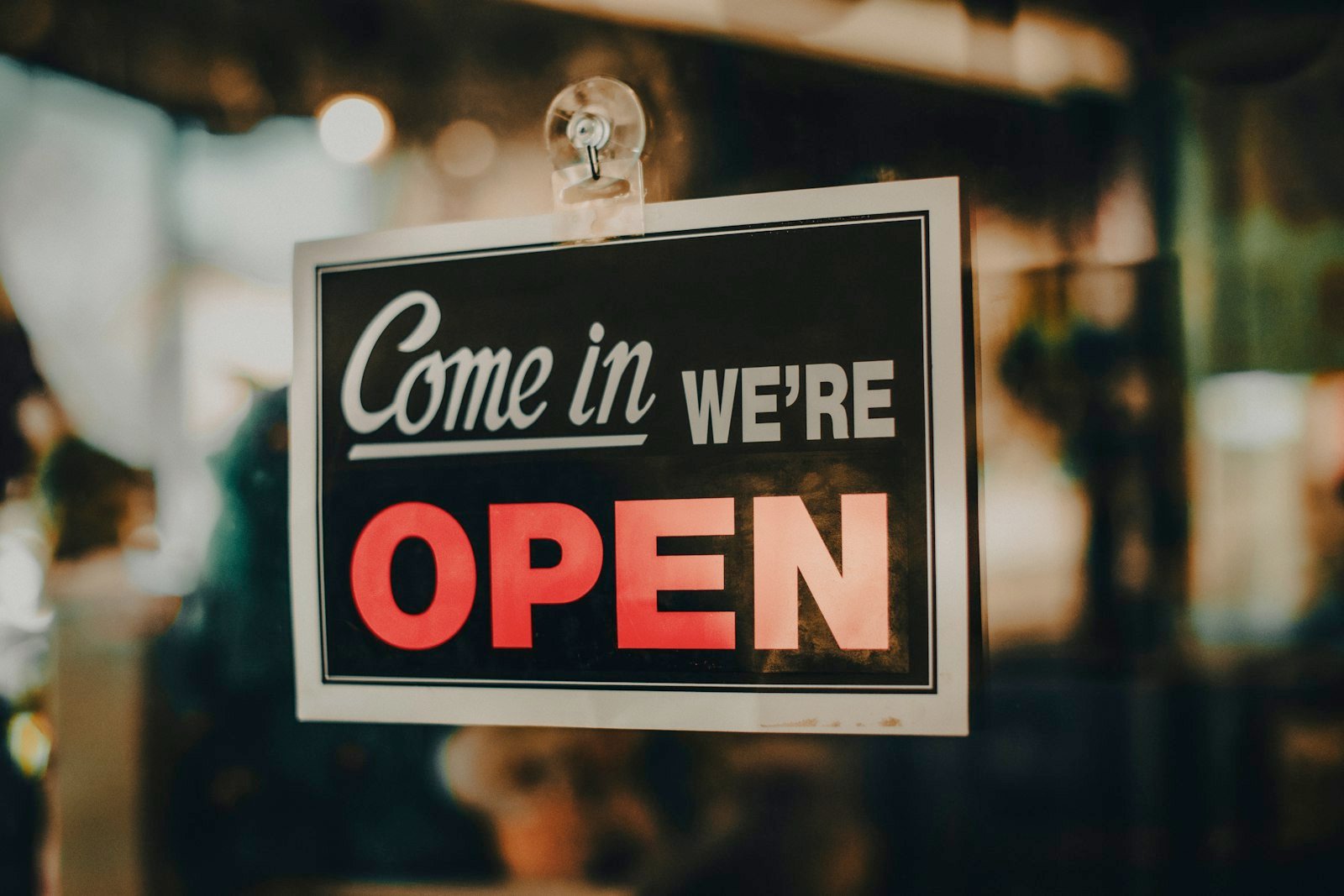 Come in, we're open sign hanging in the window of a small business