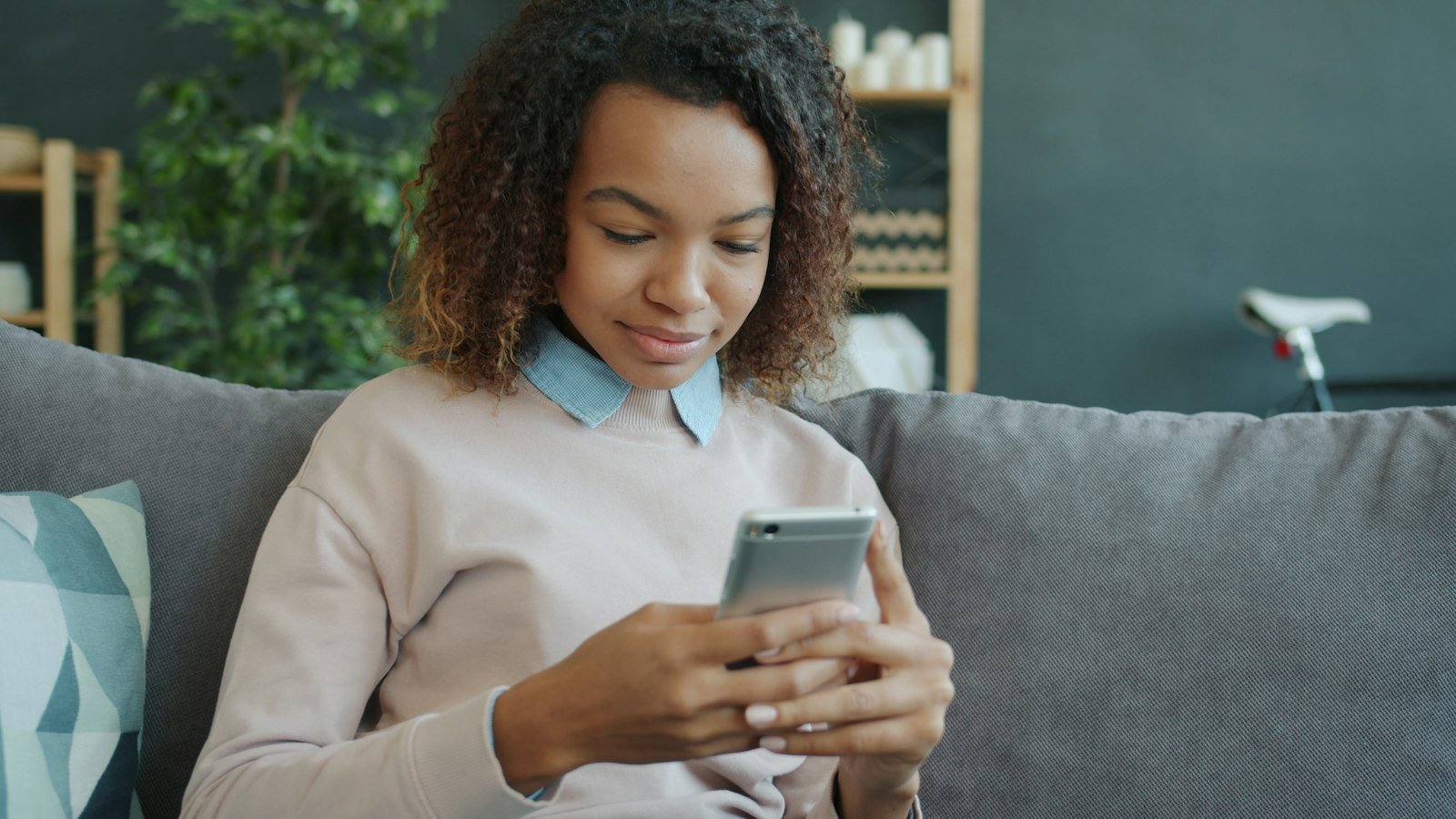 A customer smiling as she reads a text message on her phone at home