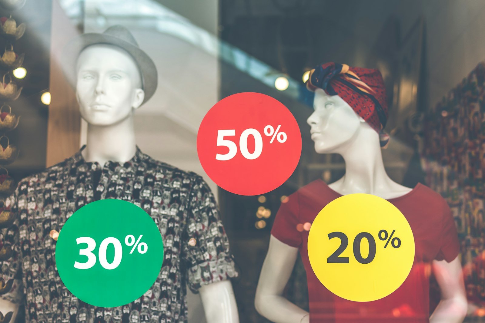 Store mannequins behind round 50%, 30% and 20% off discount signs