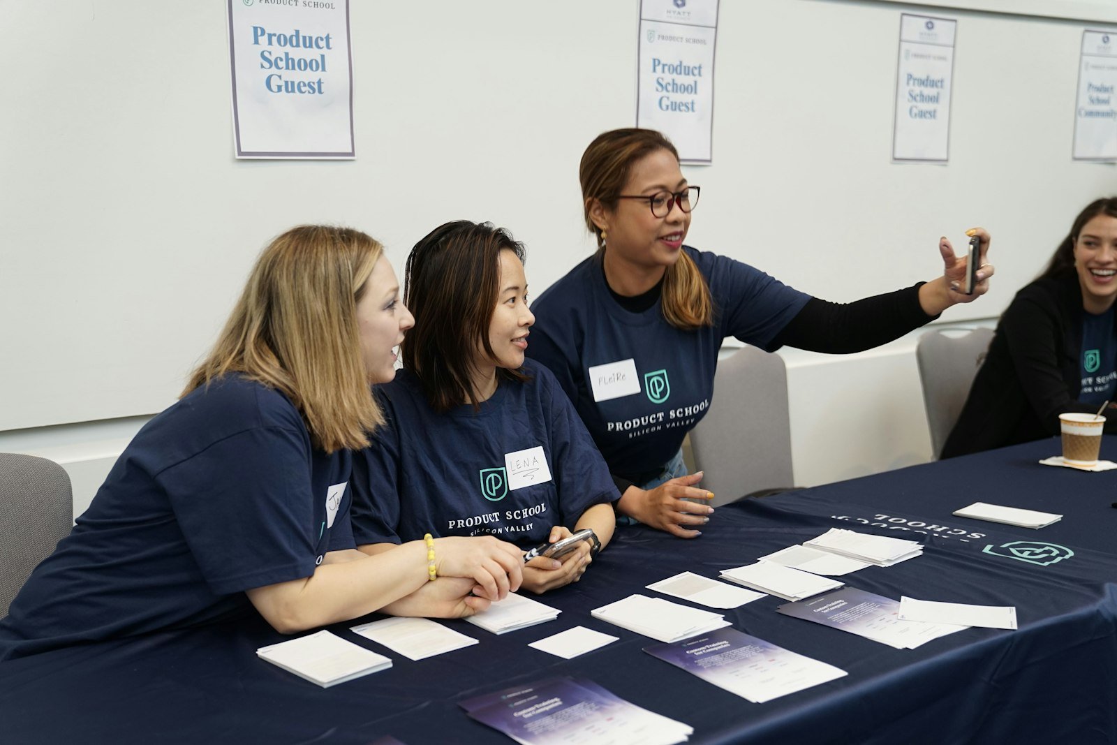 Three event staff in matching shirts at an exhibitor table with brochures