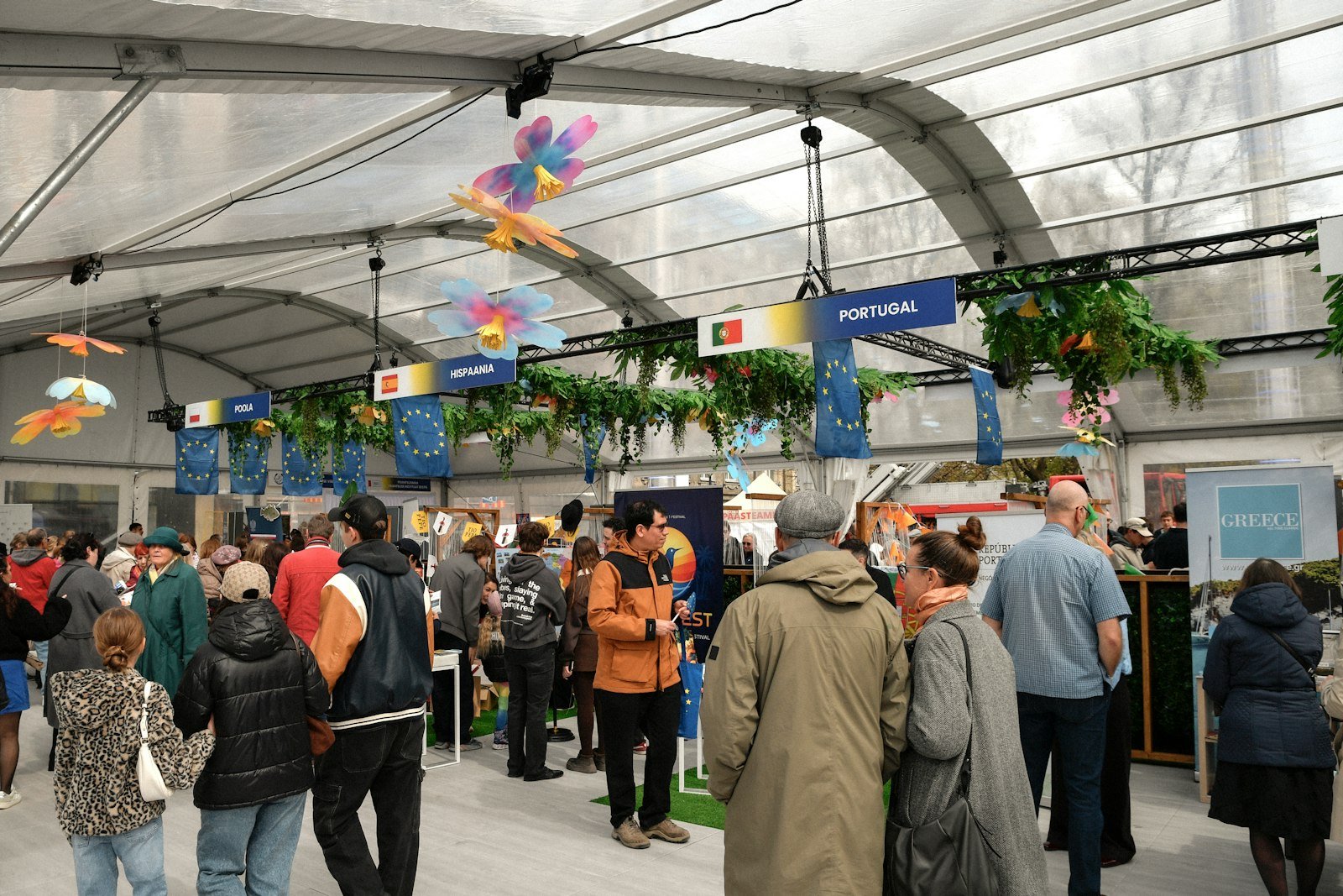 Visitors walking between decorated stalls inside a large event tent