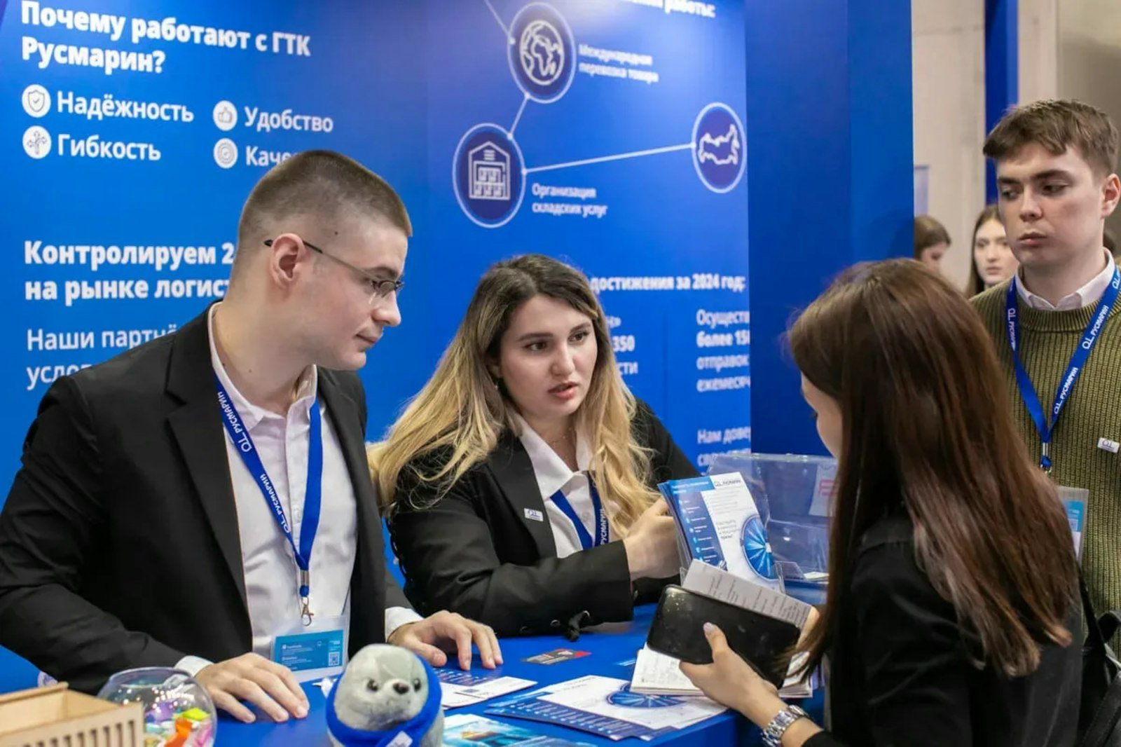 Exhibitors at a branded trade show booth talking with a visitor across the counter