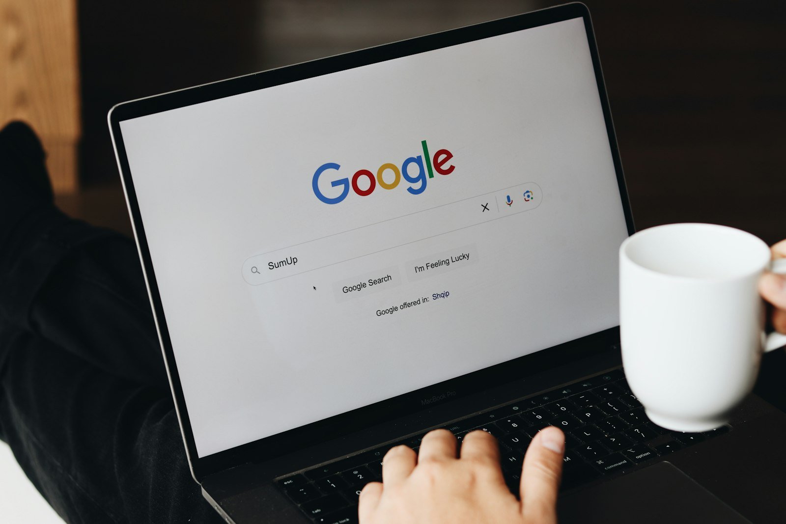 A person typing on a laptop with the Google search page open
