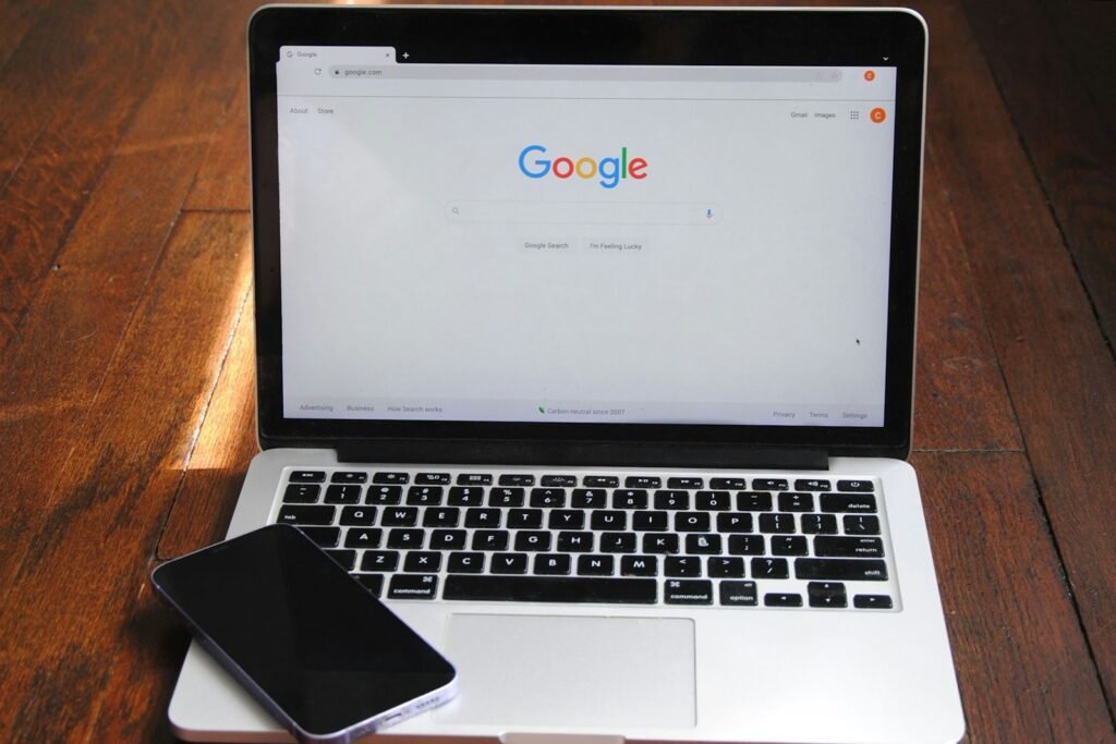 A laptop on a wooden desk showing the Google search home page