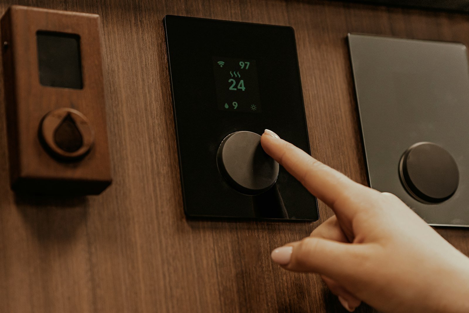Hand adjusting a wall thermostat control inside a home