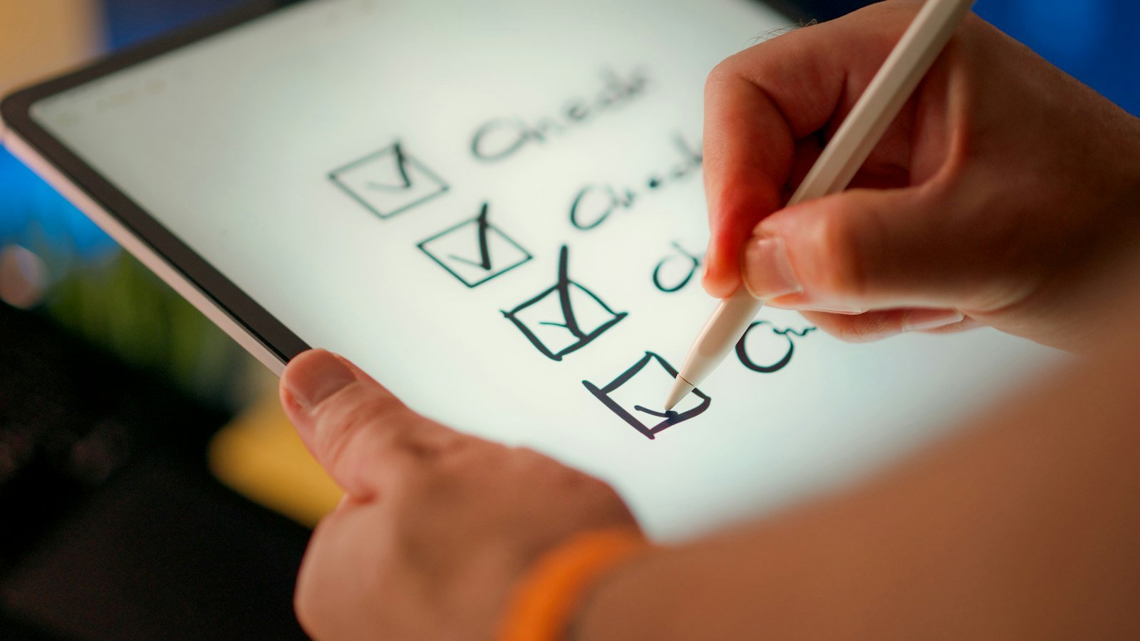 Hand using a stylus to tick off boxes on a handwritten checklist on a tablet screen