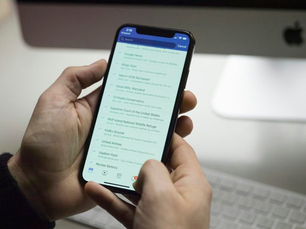 Hands holding a phone showing an email inbox full of subject lines