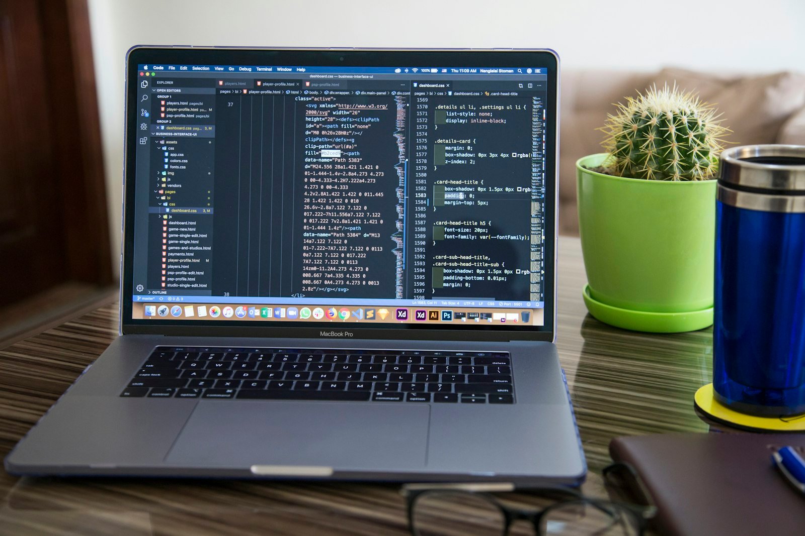 A laptop showing website code next to a small plant