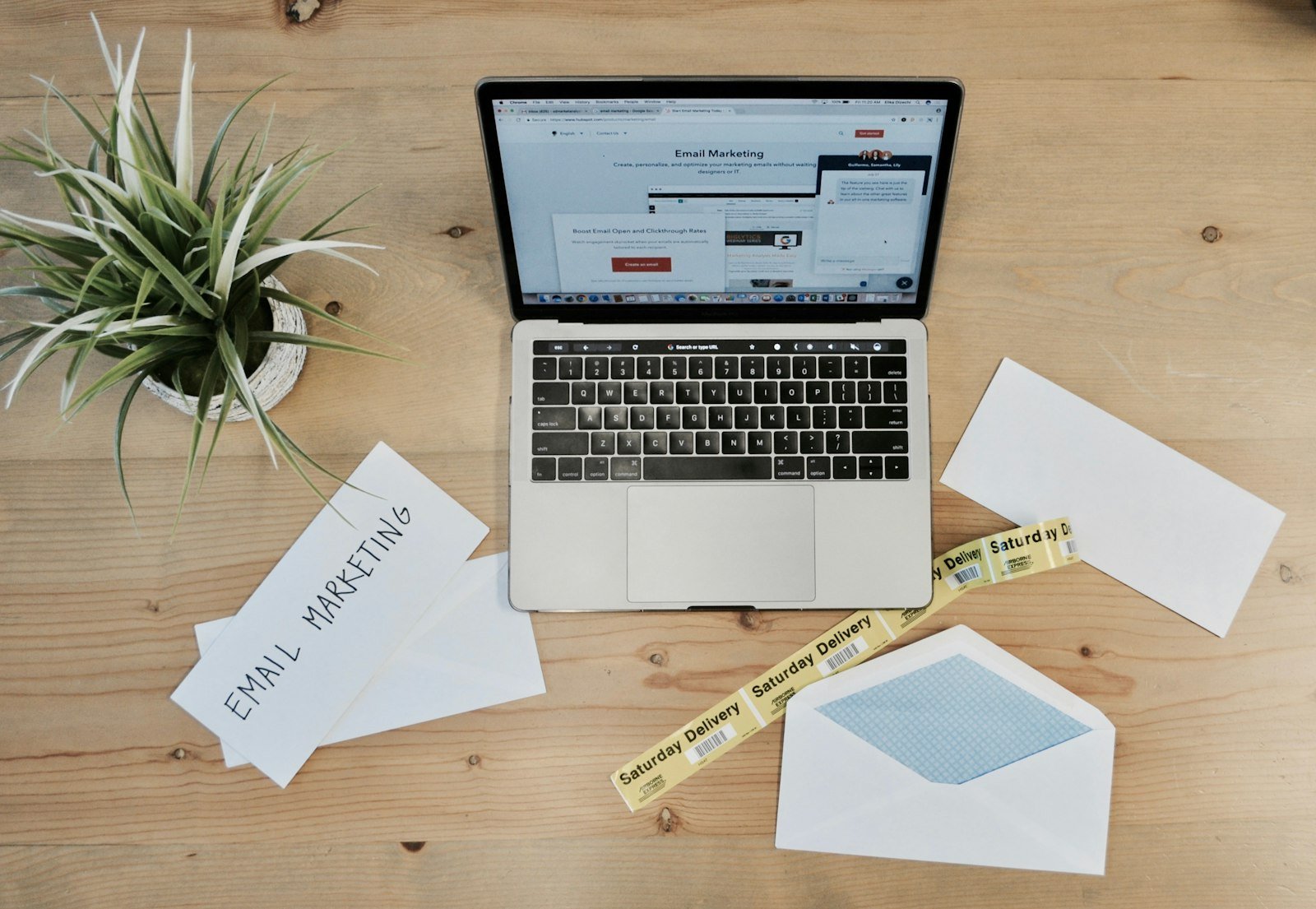 A laptop on a wooden desk surrounded by envelopes and letters
