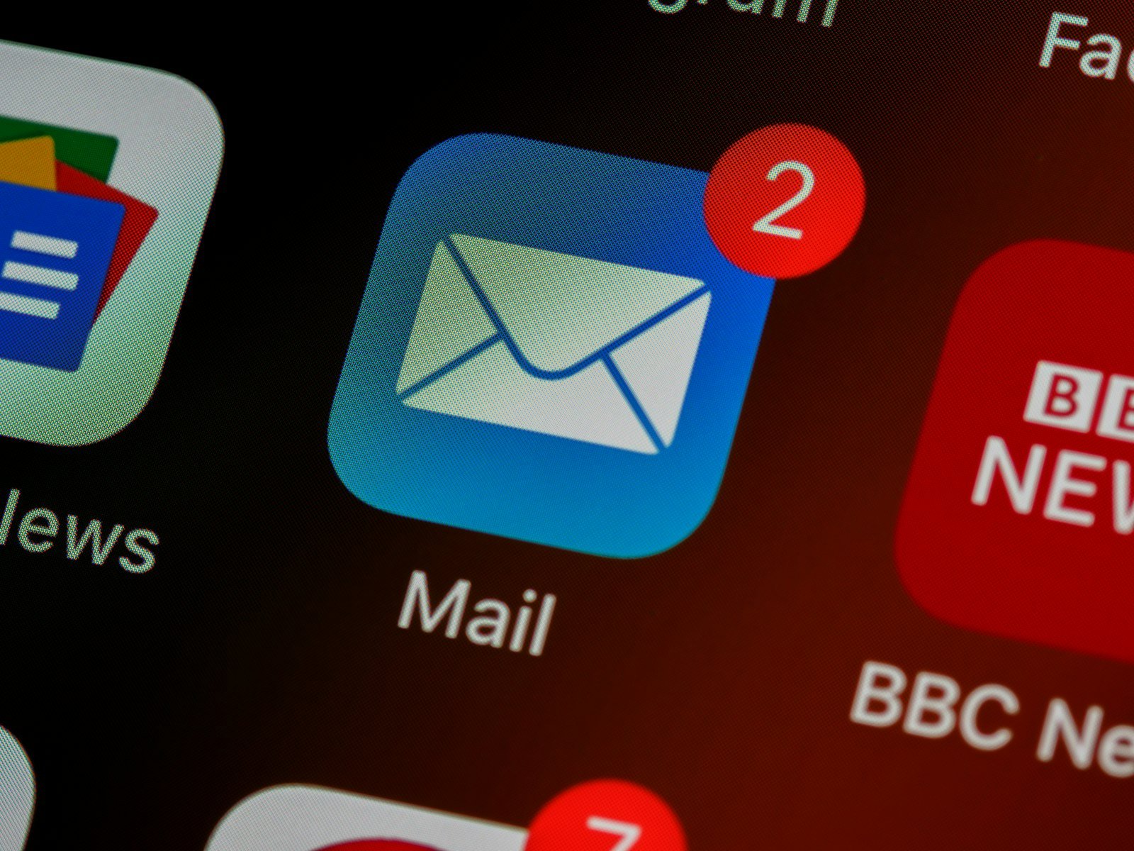 A phone home screen with the Mail app showing two unread emails