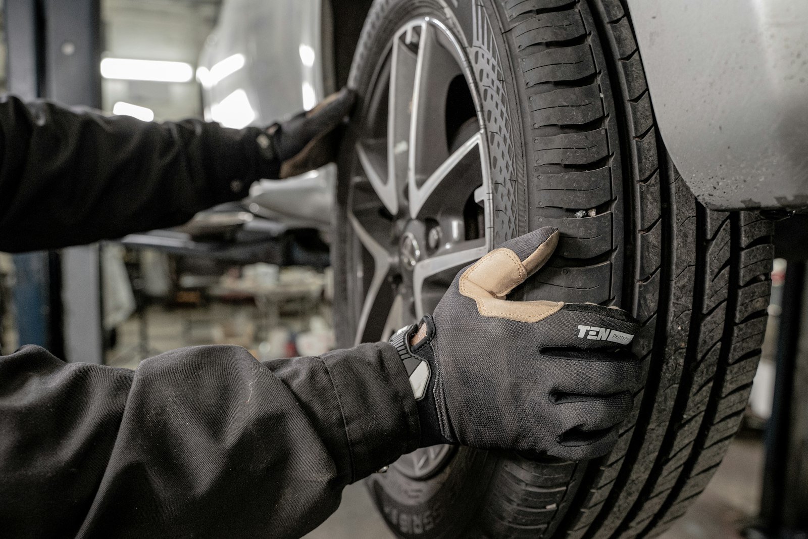 Mechanic in gloves fitting a tire onto a car in a garage