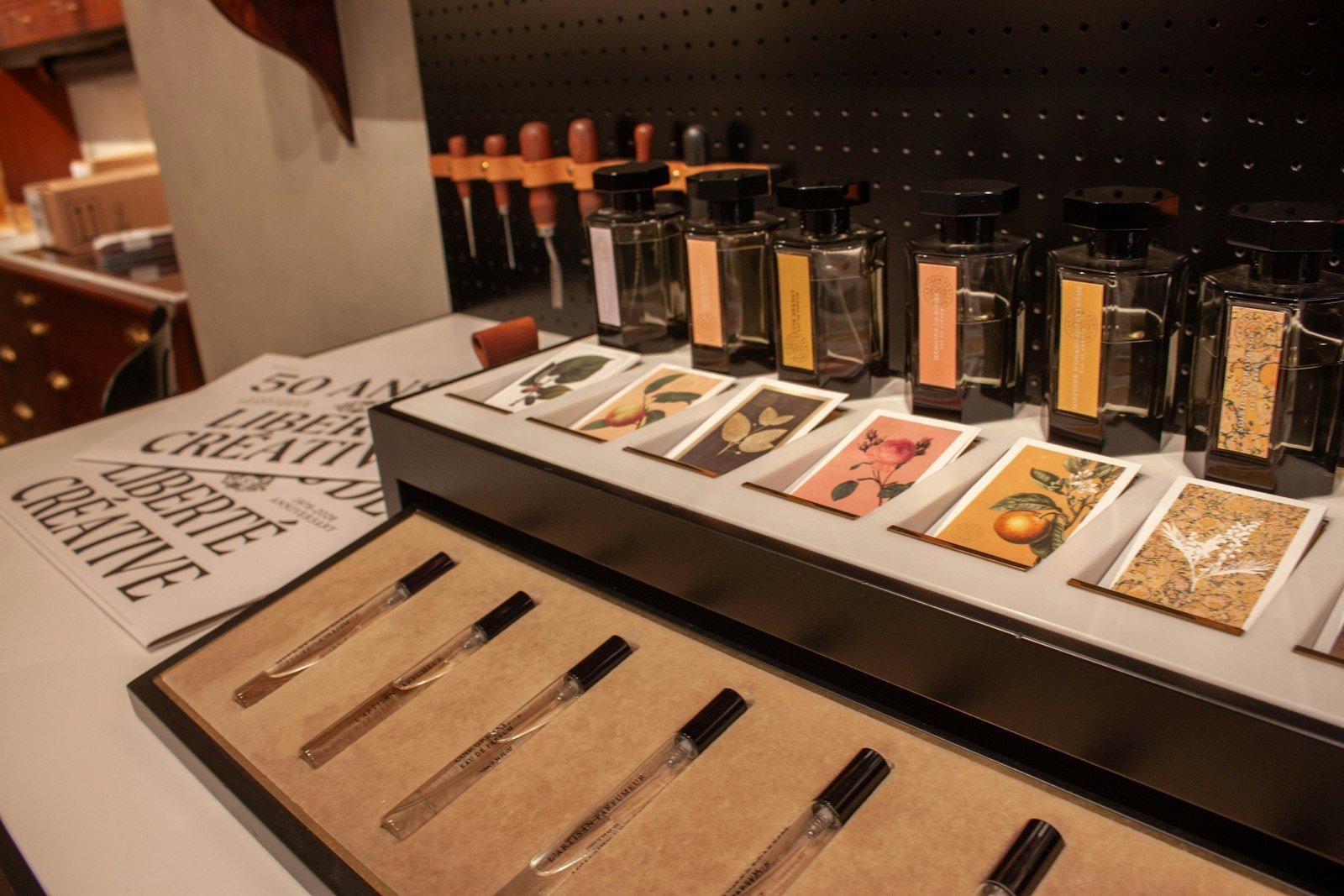Perfume bottles on a shop counter with a tray of small sample vials and scent cards in front