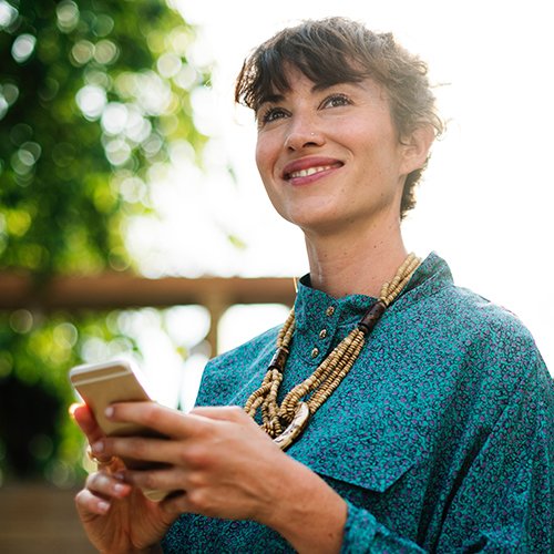 A woman scrolling through social media on her phone outdoors