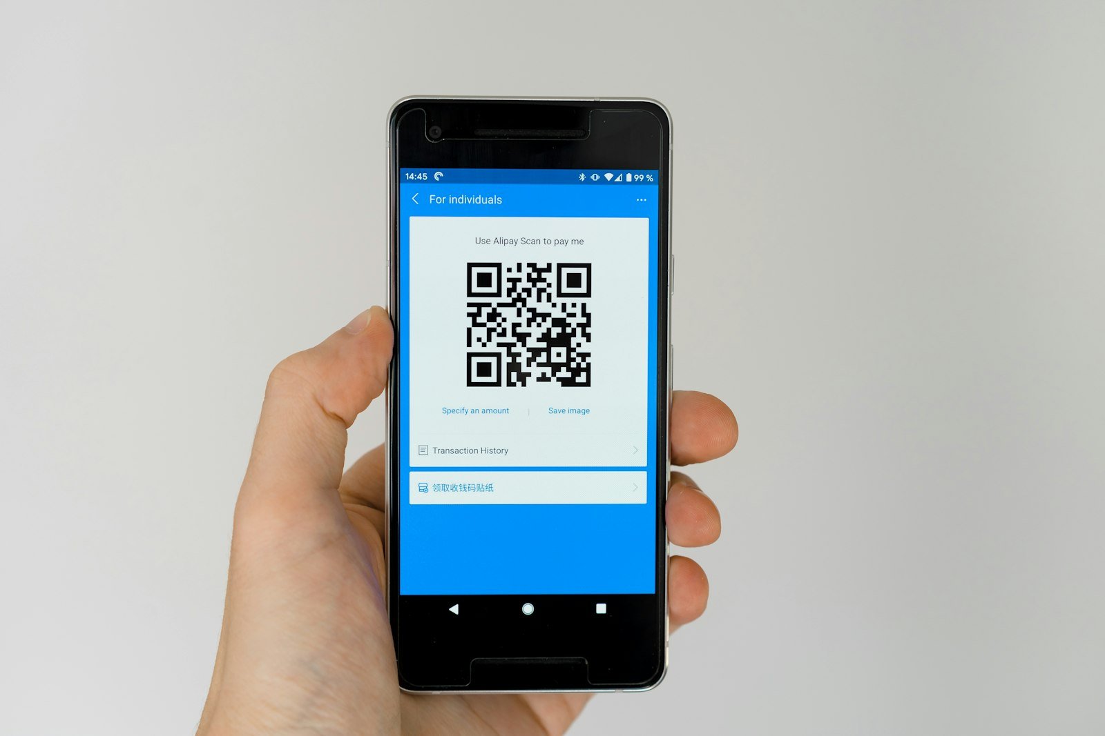 A hand holding a phone that displays a QR code