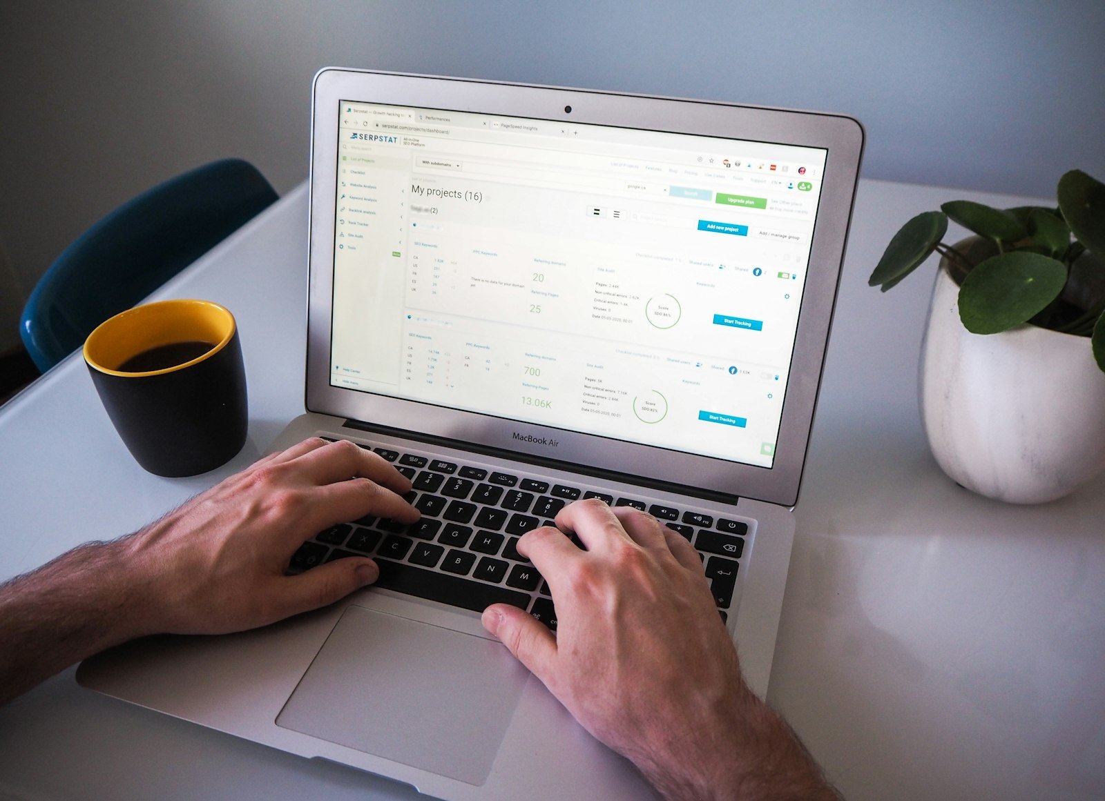 Person typing on a laptop at a white desk with a web app open on screen