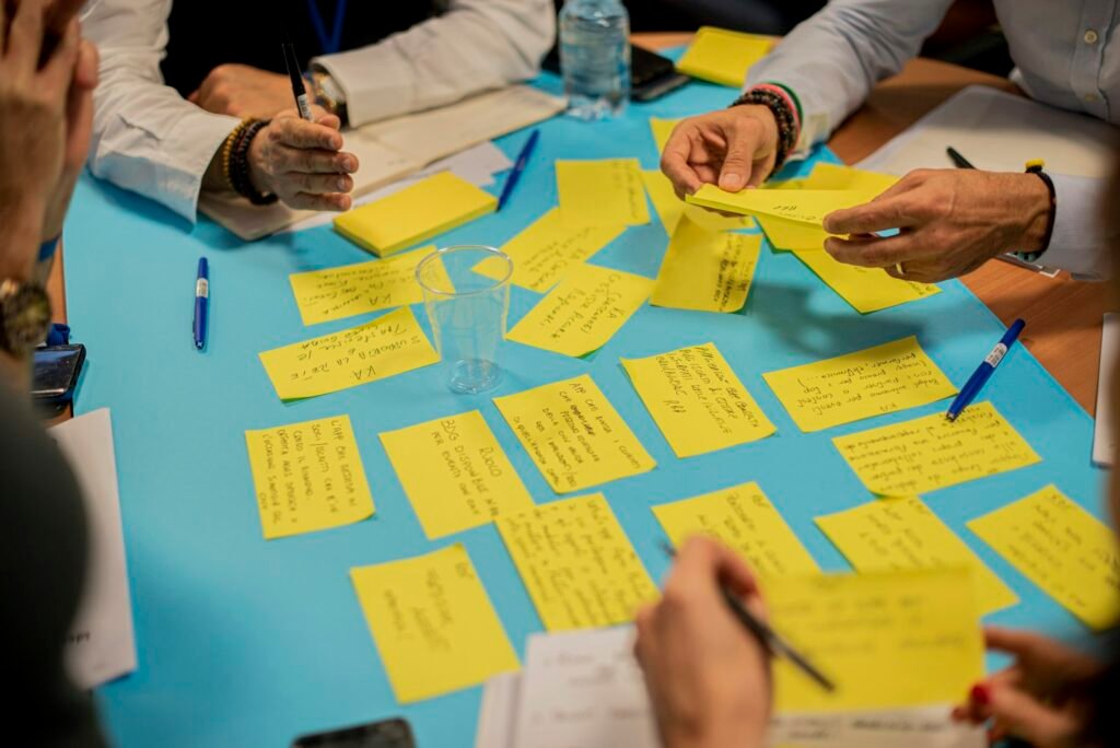 A team sorting sticky notes on a table during a research workshop