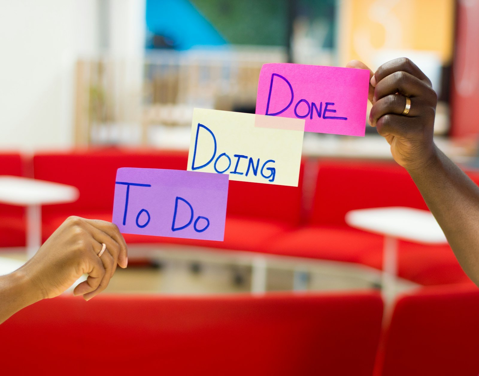 Hands holding three sticky notes labelled To Do, Doing and Done